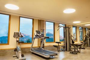 a gym with treadmills and ellipticals in a room with windows at Taj Theog Resort & Spa Shimla in Shimla