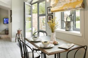 a table with two cups and chairs and a window at The Potting Shed in Weston under Lizard