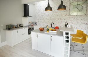 a kitchen with white cabinets and a clock on the wall at The Potting Shed in Weston under Lizard