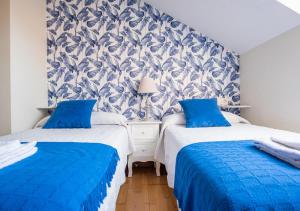 2 letti in una camera con pareti bianche e blu di Apartamento Irene céntrico con Wifi y parking coche tamaño medio Cangas de Onís a Cangas de Onís