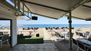 a deck with tables and chairs on the beach at First line apartment in Flogita
