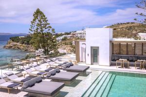 a group of lounge chairs next to a swimming pool at Grace Mykonos in Agios Stefanos