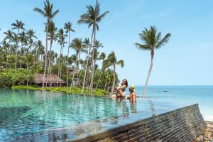 kobieta i dwoje dzieci w basenie bez krawędzi na plaży w obiekcie Four Seasons Resort Koh Samui w mieście Mae Nam