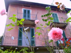 a pink building with pink roses in front of it at La Cà del Menèc in Lierna