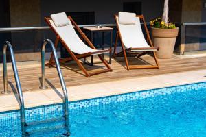 two chairs and a table next to a swimming pool at Vellum Luxury Living in Kallithea Halkidikis