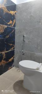 a bathroom with a toilet and a marble wall at Kailash Guest Home in Mysore