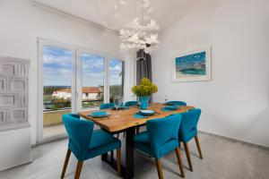 comedor con mesa de madera y sillas azules en Holiday Home PUNAT OASIS with breathtaking Sunset & Sea View, en Punat