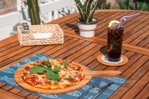 a pizza sitting on a wooden table with a drink at Bronze Hotel in Oludeniz