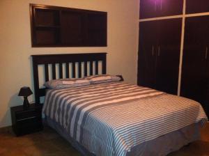 ein Schlafzimmer mit einem Bett mit einer gestreiften Decke in der Unterkunft Walkervilla in De Deur