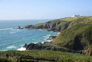 a view of the ocean with a lighthouse on a cliff at Bishop Rock in Landewednack