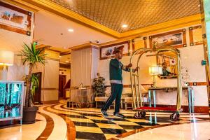 Al Ritz Al Madinah في المدينة المنورة: رجل يقف في لوبي الفندق مع عربة لحمل الحقائب