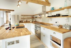 a kitchen with white cabinets and wooden counter tops at Rosebank Barn in Bibury