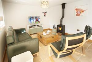 a living room with a couch and chairs and a stove at Rosebank Barn in Bibury