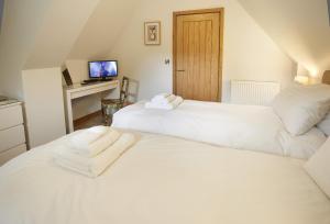 twee witte bedden naast elkaar in een kamer bij Rosebank Barn in Bibury