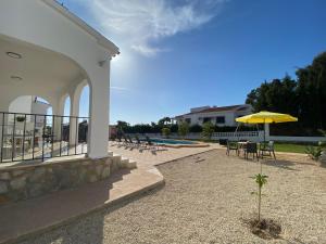 een patio met een gele parasol en tafels en stoelen bij Villa con piscina, soleada, tranquila y céntrica in Calpe