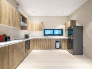 a kitchen with wooden cabinets and a black refrigerator at Mabaat-Executive-Hittin 519 3BR-5-2 in Riyadh +13 photos