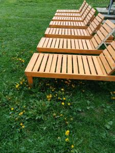 a row of wooden benches sitting in the grass at Sadyba u Vani in Volovets