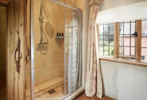 ein Bad mit einer Dusche und einem Fenster in der Unterkunft Elinor Fettiplace in Pauntley