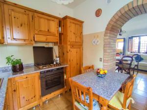 a kitchen with wooden cabinets and a table with a bowl of fruit at Apartment La Pergola by Interhome in Roccastrada