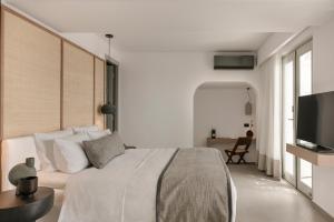 1 dormitorio con 1 cama y TV de pantalla plana en Grace Mykonos, en Agios Stefanos