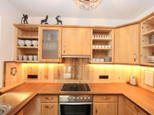 - une cuisine avec des placards en bois et une cuisinière dans l'établissement Apartment Tristner Appart by Interhome, à Schwendau
