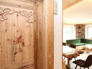 Cette chambre est dotée d'un mur en bois avec une table et un canapé vert. dans l'établissement Apartment Tristner Appart by Interhome, à Schwendau