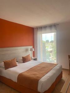 a bedroom with a large bed with a large window at Hotel Funtana Marina in LʼÎle-Rousse