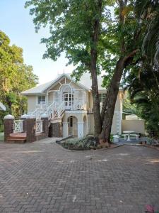 a white house with a tree in front of it at Caribbean Estates Villa 7B in Port Edward +6 photos