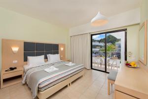 a bedroom with a large bed and a balcony at Sunny Days Hotel in Ixia