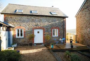 a brick house with a wooden deck in front of it at Seekings Cottage in Knowstone