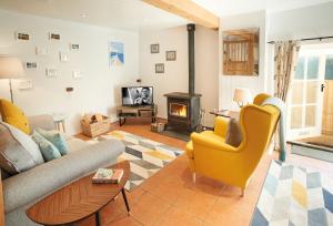 a living room with a couch and chairs and a fireplace at Seekings Cottage in Knowstone