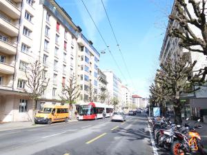 uma rua da cidade com um autocarro e carros e edifícios em Apartment Pérolles by Interhome em Fribourg