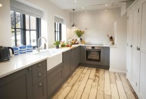 a kitchen with gray cabinets and a wooden floor at The Dairy Worcestershire in Eckington