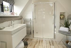 a white bathroom with a shower and a sink at The Dairy Worcestershire in Eckington