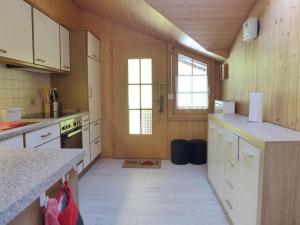 a kitchen with wooden walls and white cabinets at Apartment Chalet Vamika by Interhome in Niederried