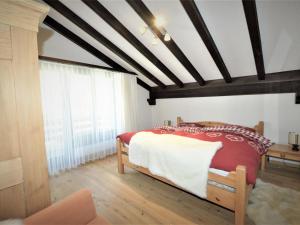 een slaapkamer met een rood en wit bed en een raam bij Apartment Casa La Schmetta 45 by Interhome in Lenzerheide