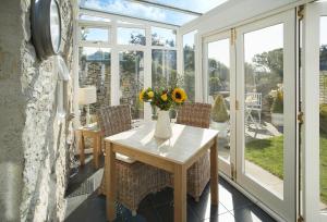 a conservatory with a table with a vase of flowers on it at Winsmore Cottage in Bakewell