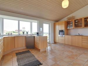 a large kitchen with wooden cabinets and a large window at Holiday Home Amalia - 500m from the sea in NW Jutland by Interhome in Hjørring