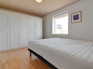 a white bedroom with a large bed and a window at Holiday Home Amalia - 500m from the sea in NW Jutland by Interhome in Hjørring
