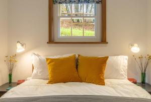 a bedroom with a bed with yellow pillows and a window at Inkpen Cottage in Robertsbridge