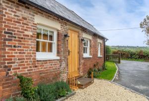 a brick house with a yellow door and a driveway at Inkpen Cottage in Robertsbridge