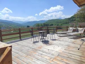 a deck with chairs and a table with a view of mountains at B&B Max & Lory in Neviano degli Arduini