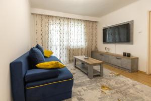 sala de estar con sofá azul y TV en Luxury 2 bedroom holiday apartment, en Piteşti