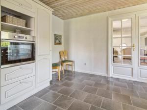 uma cozinha com armários brancos e piso em azulejo em Holiday Home Aku - 24km from the sea in Western Jutland by Interhome em Højer