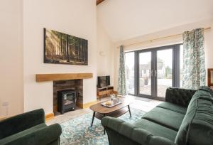 a living room with two green couches and a fireplace at The Old Stables at Bradley's Farm in Holt