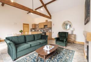 a living room with a green couch and a table at The Old Stables at Bradley's Farm in Holt