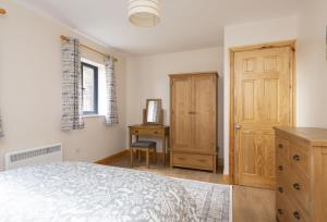 1 dormitorio con cama, escritorio y puerta en The Old Stables at Bradley's Farm en Holt