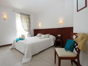 a bedroom with a large bed and a chair at Studio Le studio by Interhome in Saint-Jouan-des-Guérets