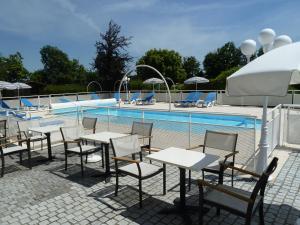 a group of tables and chairs next to a swimming pool at Studio Le studio by Interhome in Saint-Jouan-des-Guérets