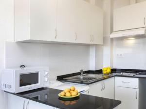 - une cuisine blanche avec un bol de fruits sur un comptoir dans l'établissement Apartment Montseny by Interhome, à Sant Antoni de Calonge